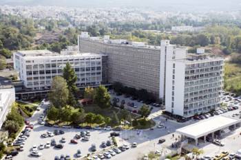 Photo taken with a drone showing two large buildings in front of which there is a parking lot with cars parked around it